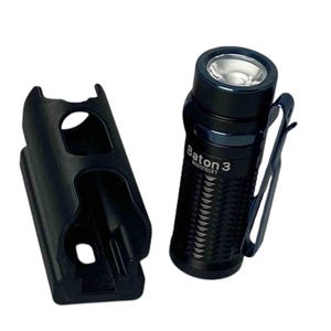 May include: A black flashlight with a textured body and a clip. The flashlight has the text "Baton 3" and "N0005137" printed on the side. The flashlight is next to a black plastic holster.
