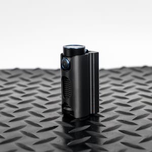 Puede incluir: Una linterna negra con un anillo azul alrededor de la cabeza y una funda de transporte negra.