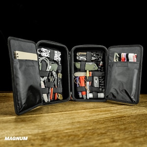 May include: A black zippered carrying case with multiple compartments, filled with various tools and accessories. The case is open, revealing the contents, which include a variety of tools, such as pliers, screwdrivers, and knives.