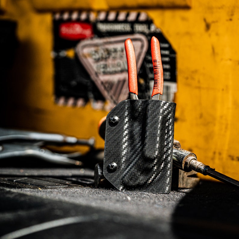 Puede incluir: Una funda de fibra de carbono negra con dos alicates de mango naranja. La funda est&aacute; dise&ntilde;ada para sujetar los alicates de forma segura en su lugar.