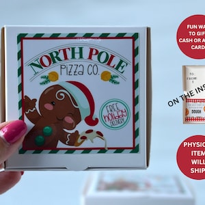 May include: A white pizza box with a red and green striped border. The box features a cartoon gingerbread man holding a slice of pizza. The text on the box reads "North Pole Pizza Co." and "Free Holiday Delivery".