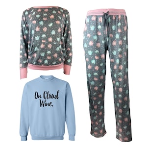Könnte beinhalten: Ein blauer und grauer Pyjama-Set mit rosa Besatz. Das Oberteil hat ein Muster aus rosa und blauen Kaffeetassen. Die Hose hat das gleiche Muster. Das Set wird mit einem separaten blauen Sweatshirt geliefert, auf dem der Text "On Cloud Wine." in Schwarz gedruckt ist.