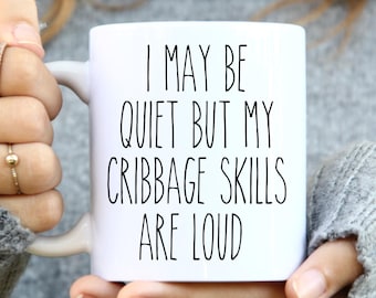 May include: White ceramic mug with black text that reads "I may be quiet but my cribbage skills are loud".