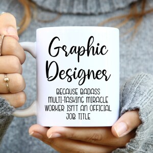 May include: White ceramic mug with black text that reads "Graphic Designer because badass multi-tasking miracle worker isn't an official job title."