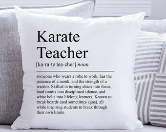 May include: A white square throw pillow with the words "Karate Teacher" printed in black. The definition of a karate teacher is also printed on the pillow. The pillow is on a light gray couch with other pillows.