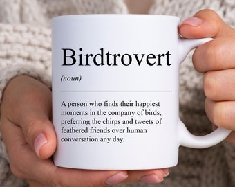 May include: White ceramic mug with a black and white definition of the word "Birdtrovert" which is defined as "A person who finds their happiest moments in the company of birds, preferring the chirps and tweets of feathered friends over human conversation any day."