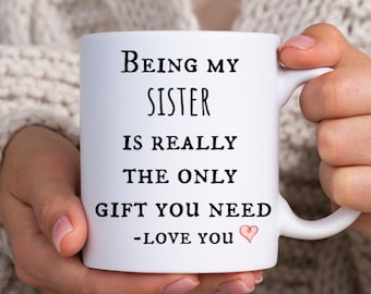 Puede incluir: Taza de cerámica blanca con texto negro que dice "Ser mi hermana es realmente el único regalo que necesitas -Te quiero" con un corazón rosa.