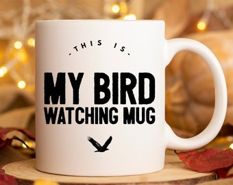 May include: White ceramic mug with black text that reads "This is my bird watching mug" and a black silhouette of a bird flying.