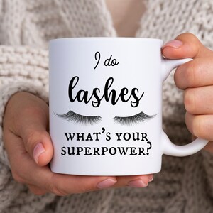 Puede incluir: Taza de cerámica blanca con texto negro que dice "I do lashes, what's your superpower?" con un par de pestañas sobre el texto.