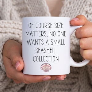 May include: White ceramic mug with black text that reads "Of course size matters, no one wants a small seashell collection". A small pink seashell is printed below the text.