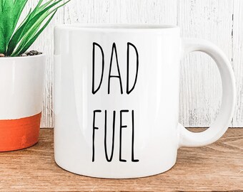 May include: White ceramic mug with black text that reads "DAD FUEL".