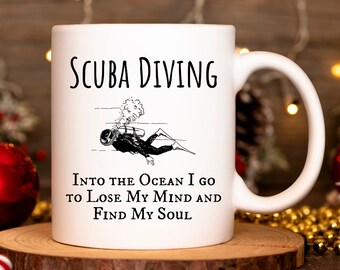 May include: White ceramic mug with a black illustration of a scuba diver and the text "SCUBA DIVING INTO THE OCEAN I GO TO LOSE MY MIND AND FIND MY SOUL".