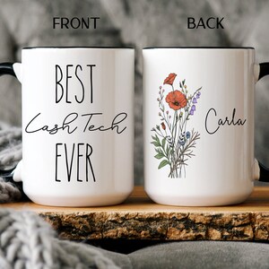 May include: White ceramic mug with a black handle and rim. The front of the mug reads "Best Cash Tech Ever". The back of the mug has a floral design with a red poppy and the name "Carla" written in cursive.