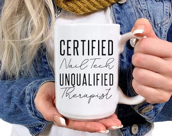 Op de afbeelding: Een witte keramische mok met zwarte tekst die "CERTIFIED Nail Tech UNQUALIFIED Therapist" luidt.