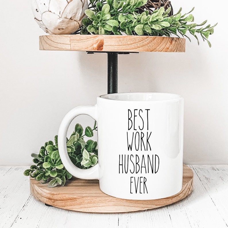 May include: White ceramic coffee mug with a black inscription that reads "Best Work Husband Ever".