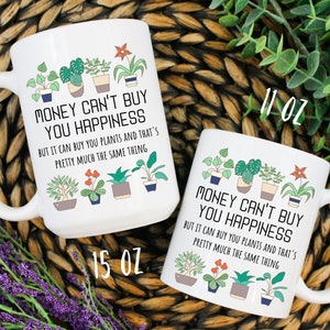 Puede incluir: Dos tazas de cer&aacute;mica blanca con un contorno negro de plantas en maceta y el texto "El dinero no puede comprar la felicidad, pero puede comprar plantas y eso es casi lo mismo". La taza de la izquierda es de 15 oz y la taza de la derecha es de 11 oz.