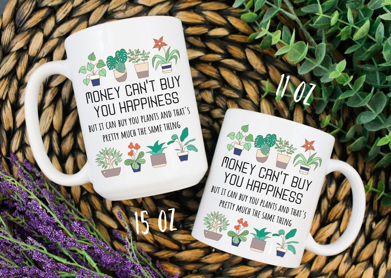 Puede incluir: Dos tazas de cer&aacute;mica blanca con un contorno negro de plantas en maceta y el texto "El dinero no puede comprar la felicidad, pero puede comprar plantas y eso es casi lo mismo". La taza de la izquierda es de 15 oz y la taza de la derecha es de 11 oz.