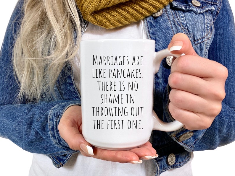 May include: White ceramic mug with a black text saying "Marriages are like pancakes. There is no shame in throwing out the first one."