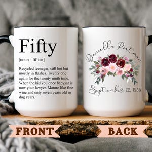 May include: White ceramic mug with a black handle and rim. The front has the word "Fifty" with a definition. The back shows a floral design with the name "Daniella Portman" and the date "September 22, 1955".