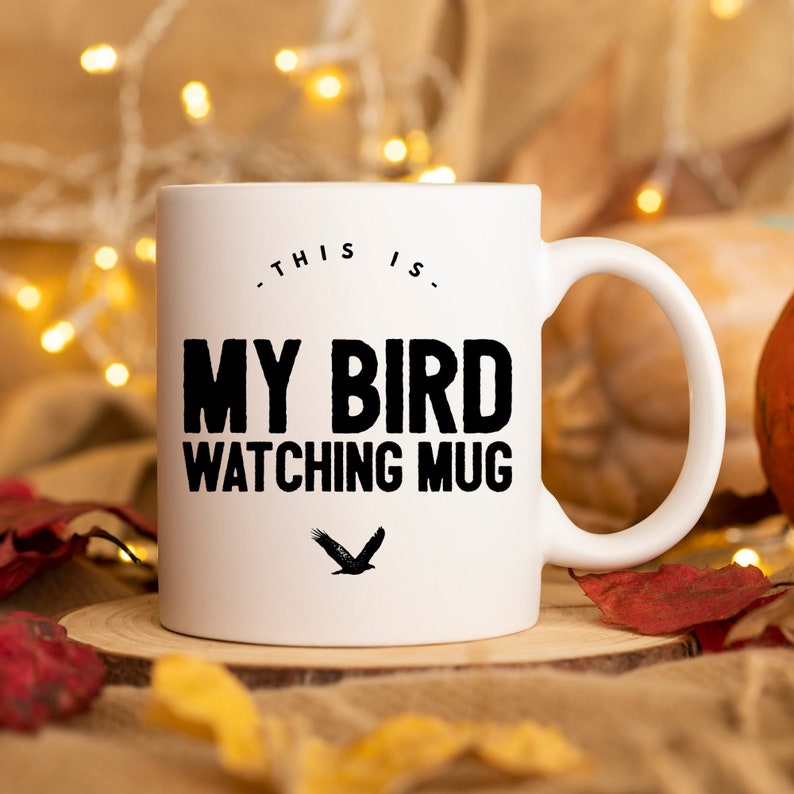 May include: White ceramic mug with black text that reads "This is my bird watching mug" and a black silhouette of a bird flying.