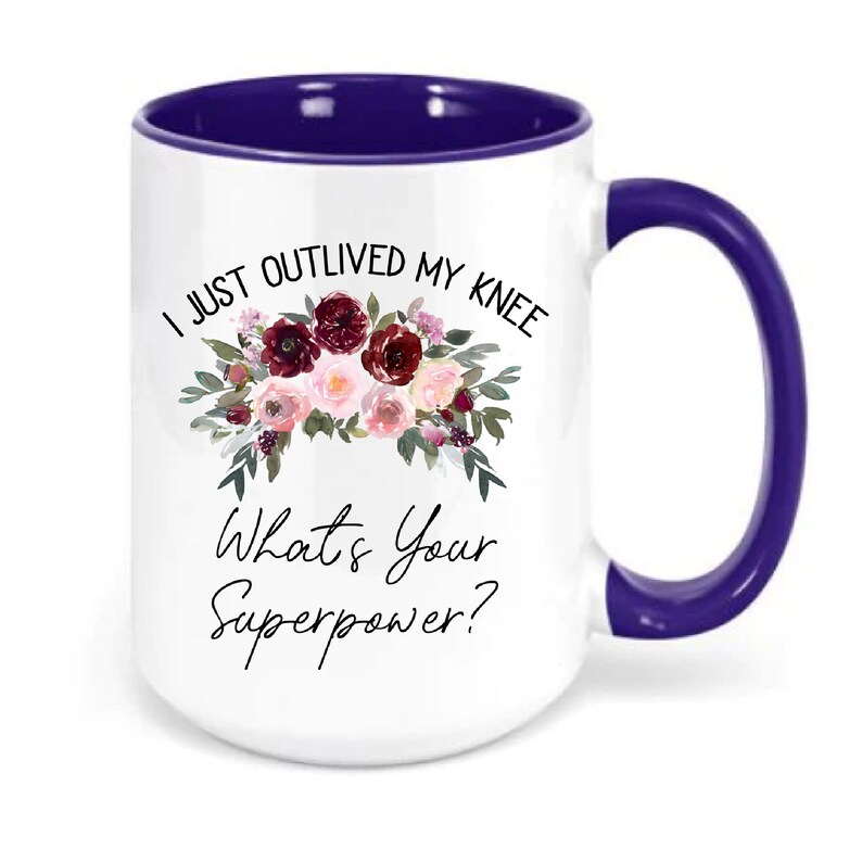 Pu&ograve; includere: Una tazza da caff&egrave; bianca con bordo e manico viola. La tazza presenta un motivo floreale e il testo "I just outlived my knee. What's your superpower?"