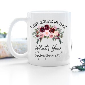 Pu&ograve; includere: Tazza da caff&egrave; in ceramica bianca con un motivo floreale e il testo "Ho appena superato il mio ginocchio. Qual &egrave; il tuo superpotere?"