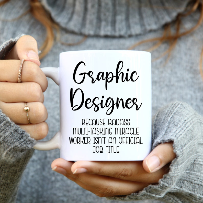May include: White ceramic mug with black text that reads "Graphic Designer because badass multi-tasking miracle worker isn't an official job title."