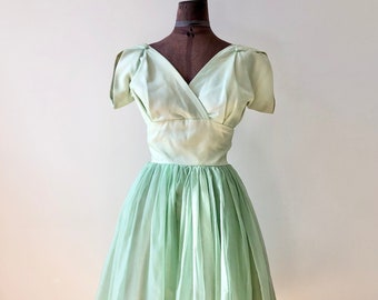 May include: A light green vintage dress with a V-neckline and short sleeves. The dress has a fitted bodice and a full skirt.