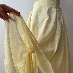 May include: A pale yellow skirt with a delicate floral pattern. The skirt is made of a lightweight fabric and has a flowing silhouette.