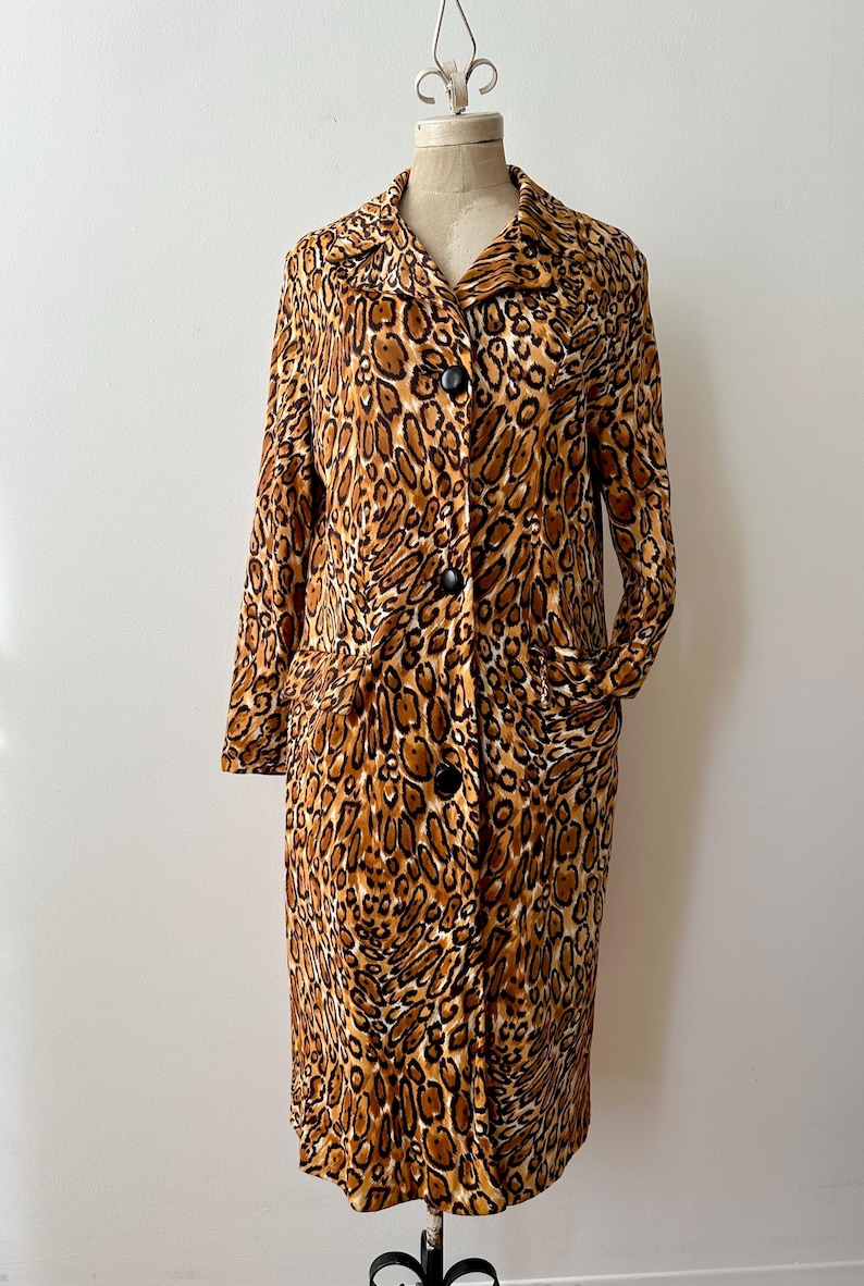 Puede incluir: Un abrigo largo con botones y estampado de leopardo. El abrigo tiene cuello, mangas largas y dos bolsillos. El abrigo se exhibe en un maniqu&iacute;.