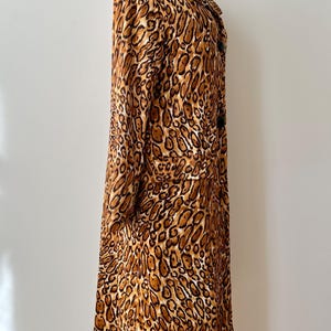 Puede incluir: Un abrigo largo con estampado de leopardo con cuello cl&aacute;sico y mangas largas. El abrigo presenta un estampado de manchas marrones y beige y se exhibe en un maniqu&iacute;. El abrigo tiene cierre de botones y bolsillos.