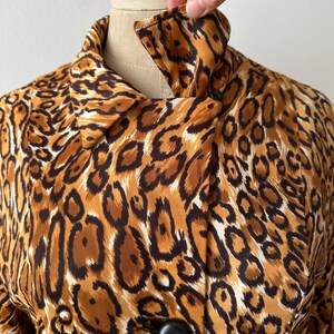 Puede incluir: Chaqueta vintage con estampado de leopardo, cuello cl&aacute;sico y grandes botones negros. La chaqueta presenta un estampado animal marr&oacute;n, beige y negro. La tela parece ser ligera, adecuada para usar en capas.