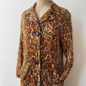 Puede incluir: Un abrigo de manga larga con estampado de leopardo, cuello y grandes botones negros. El abrigo tiene dos bolsillos delanteros y se exhibe en un maniqu&iacute;. El dise&ntilde;o de estampado animal incluye tonos de marr&oacute;n, beige y negro.