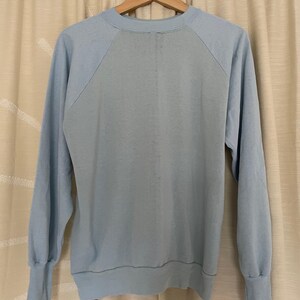 Op de afbeelding: Een lichtblauw sweatshirt met een raglanmouw ontwerp. Het sweatshirt heeft een ronde hals en een geribbelde zoom.