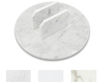 May include: White marble napkin holder with two slots. The holder is round and has a smooth surface.