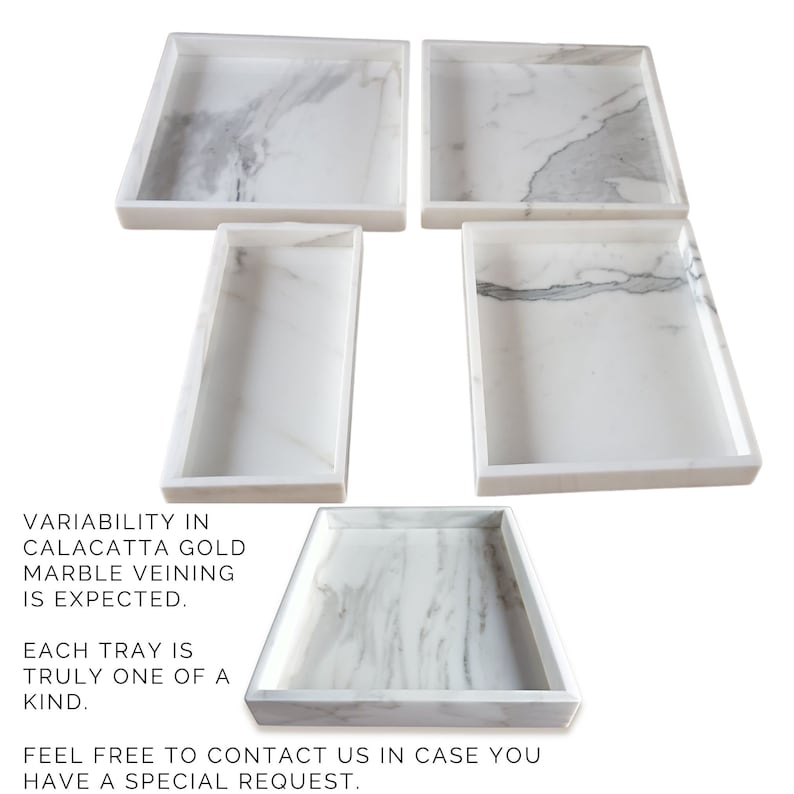 Set of five white marble trays with a gold veining pattern. Each tray is a unique shape and size. Variability in marble veining is expected. Each tray is truly one of a kind. Feel free to contact us in case you have a special request.