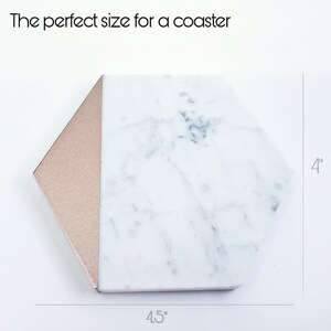 May include: White marble hexagon coaster with a rose gold edge. The coaster measures 4.5 inches wide and 4 inches tall.