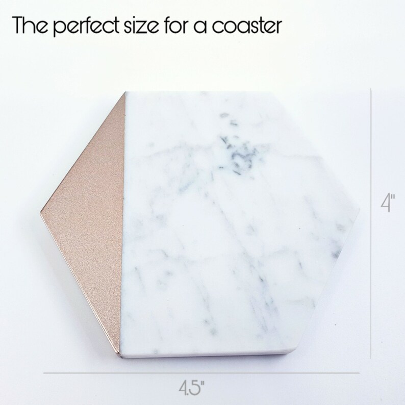 May include: White marble hexagon coaster with a rose gold edge. The coaster measures 4.5 inches wide and 4 inches tall.