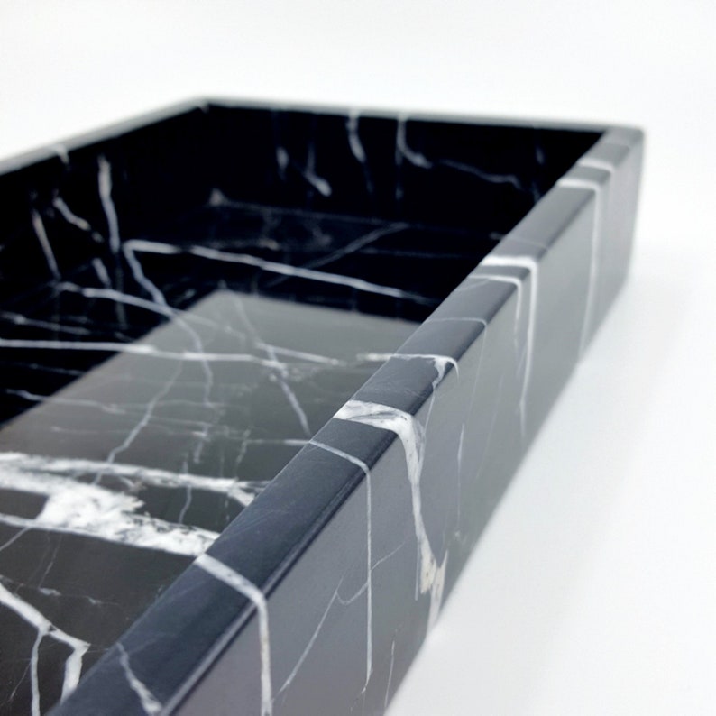 May include: A black marble tray with white veining. The tray is rectangular in shape and has a smooth, polished surface.