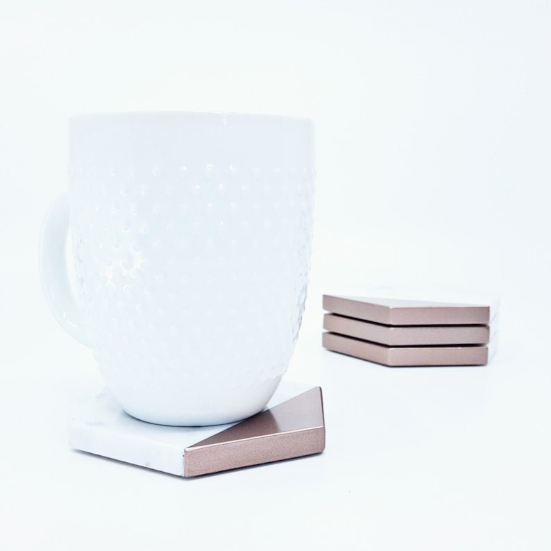 May include: White ceramic mug with a textured surface, sitting on a white and rose gold hexagonal coaster.