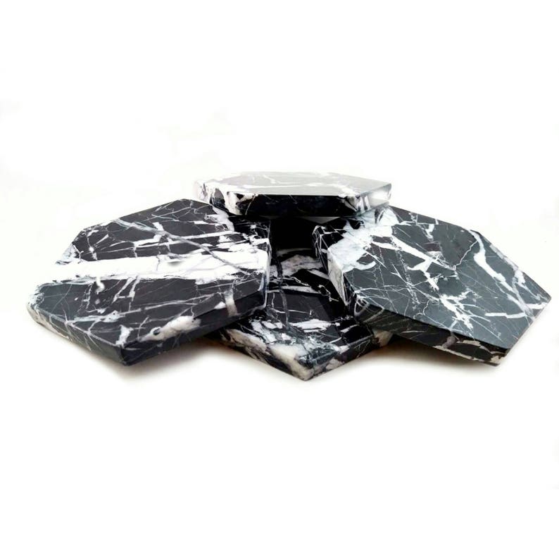 May include: Set of six black and white marble hexagonal coasters. The coasters are made of natural stone and have a unique veining pattern.