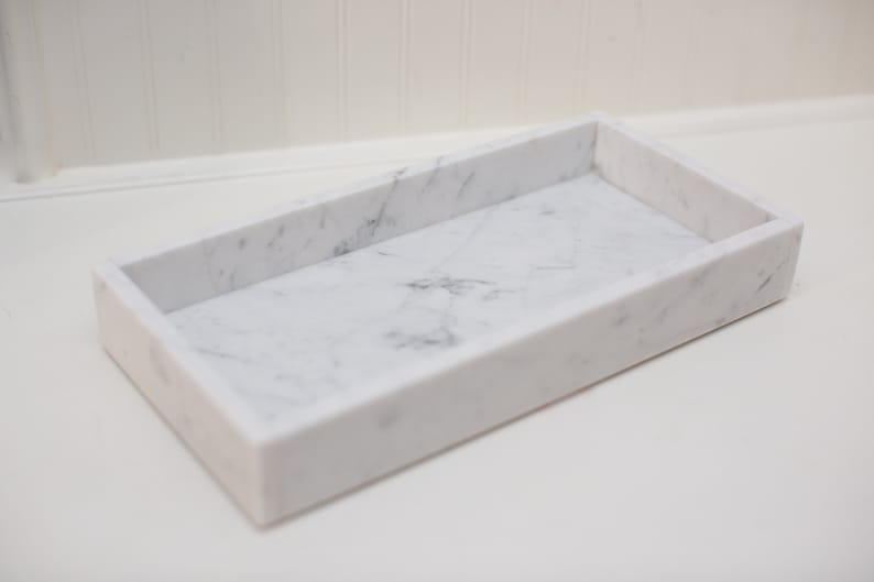 Rectangular marble tray made of Carrara marble. The tray features a smooth, white surface with subtle gray veining, highlighting the natural beauty of the marble. Ideal for decorative or organizational purposes.