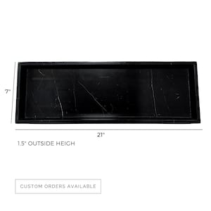 Top view of a 7" x 21" black marble serving tray with 1.5" outside height, showcasing a rectangular design with natural white veining. This durable and polished tray offers custom sizes and stone options to suit any space.