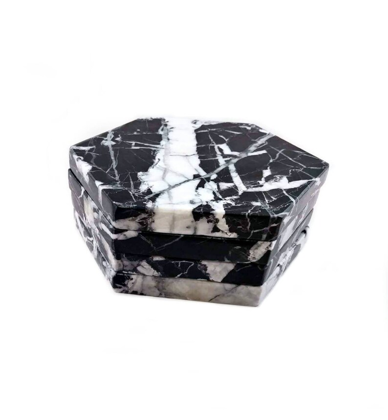 May include: Set of four black and white marble hexagonal coasters. The coasters are stacked on top of each other.