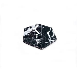 May include: Black and white marble hexagon coaster. The coaster has a swirling pattern of white veins on a black background.