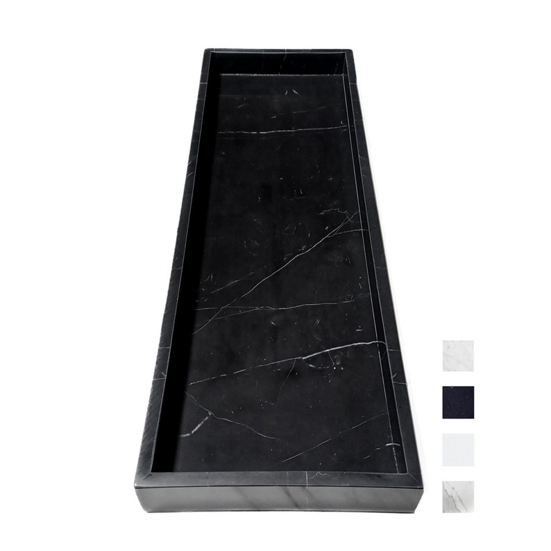 A sleek rectangular serving tray made from black marble, featuring polished edges and natural white veining for a timeless look. Measuring 7" x 21", this tray is perfect for kitchen countertops, dining displays, or vanity organization.