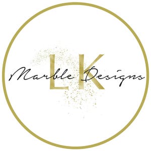 May include: A gold circle with a gold "LK" logo and the text "Marble Designs" in black cursive script. The logo is surrounded by a gold glitter effect.