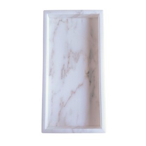 Close-up of a handmade natural marble rectangle tray showing the smooth polished surface, raised edges, and the subtle organic veining that makes each piece one of a kind.