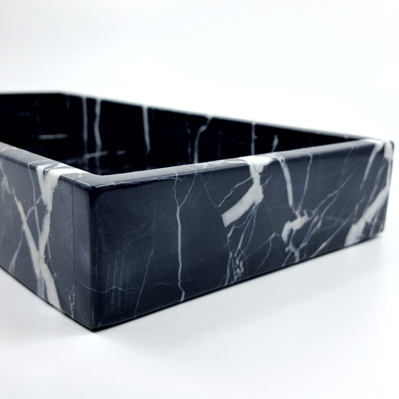 May include: A black marble tray with white veining. The tray is rectangular in shape and has a smooth, polished surface.