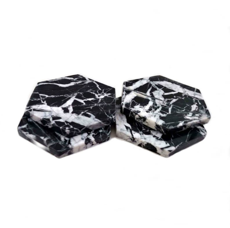 May include: Set of four black and white marble hexagonal coasters. The coasters have a natural, veined pattern.